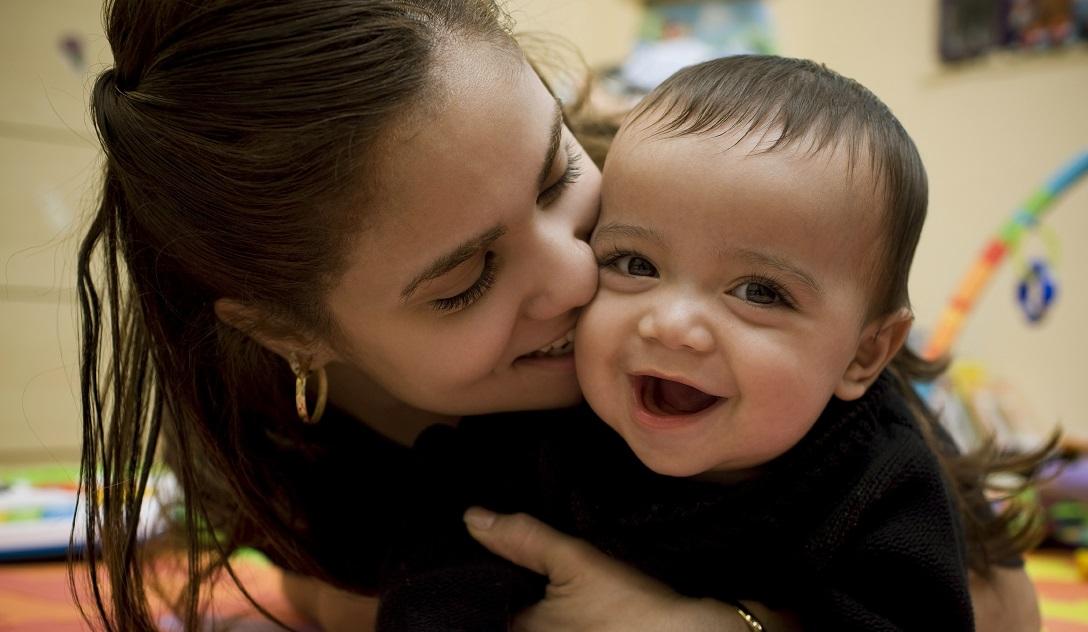 Young Mother kissing baby on the cheek 